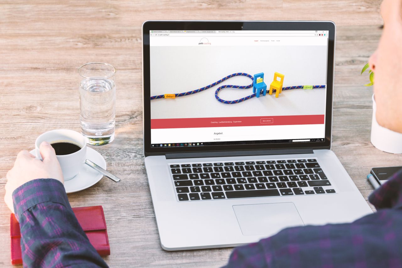 Bureau professionnel avec ordinateur portable, café et verre d’eau, mettant en valeur la technologie moderne et la productivité.